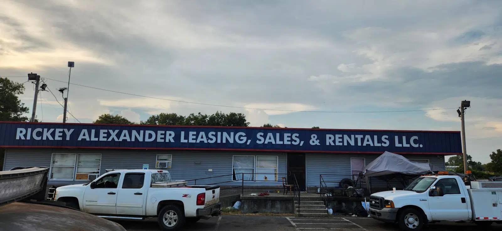 Shop building facade with parked work trucks under a cloudy sky — Rickey Alexander Mobile Truck & Trailer Repair in Forrest City